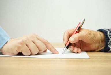 old-hand-signing-paper-with-hand-pointing