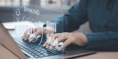 FedNow Makes Banking Faster – How Financial Institutions Can Prepare - hands rest on a laptop keyboard with a holographic image popping up that reads "Banking"
